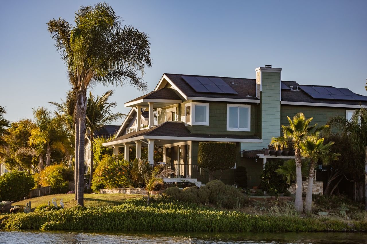who-we-are Contemporary home with solar panels and lush garden by the river.